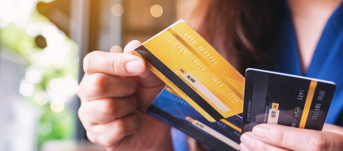 a woman holds three of her credit cards and wonders if a credit card balance transfer could help her consolidate debt