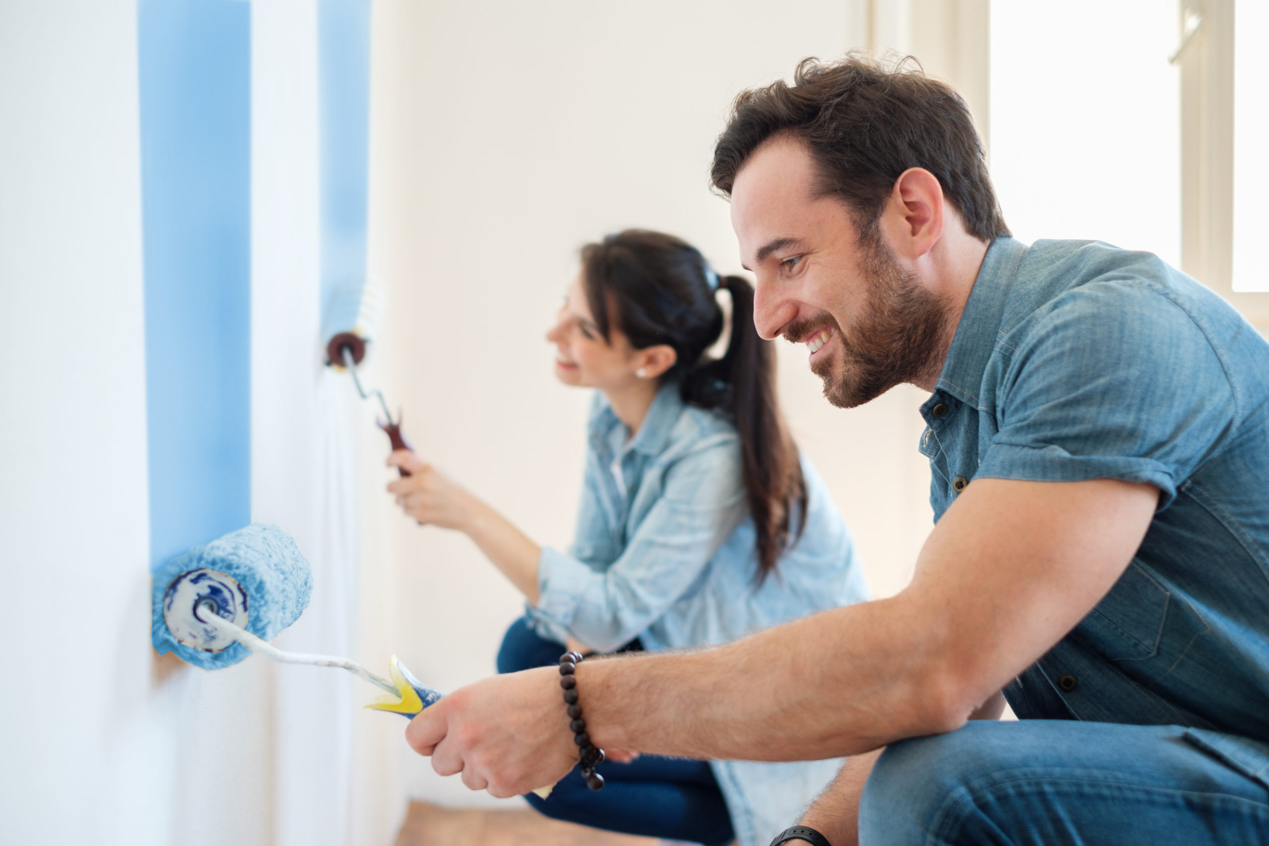 a couple works together to build home equity in their home by adding fresh coats of paint to the walls