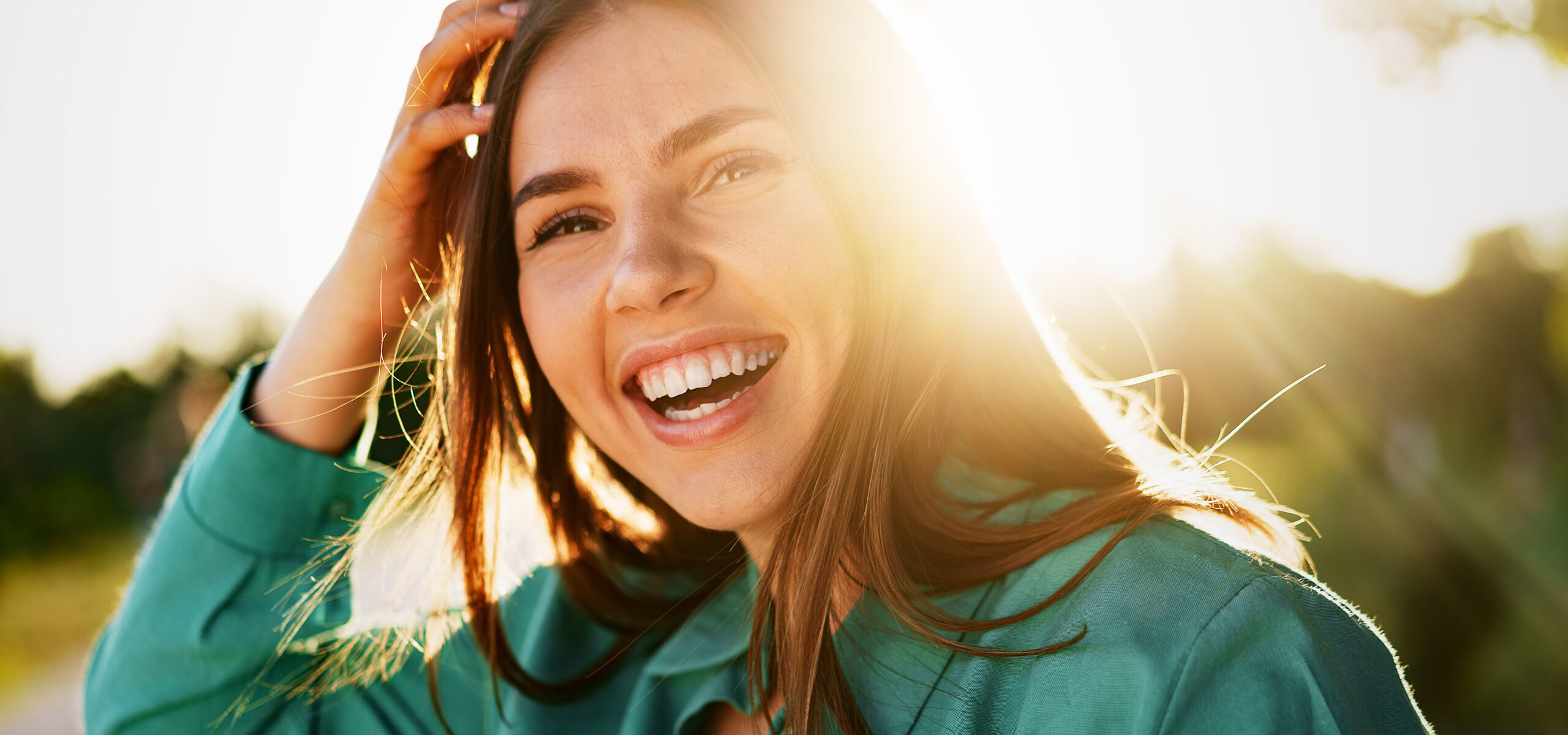 A woman in a green shirt smiling in a park