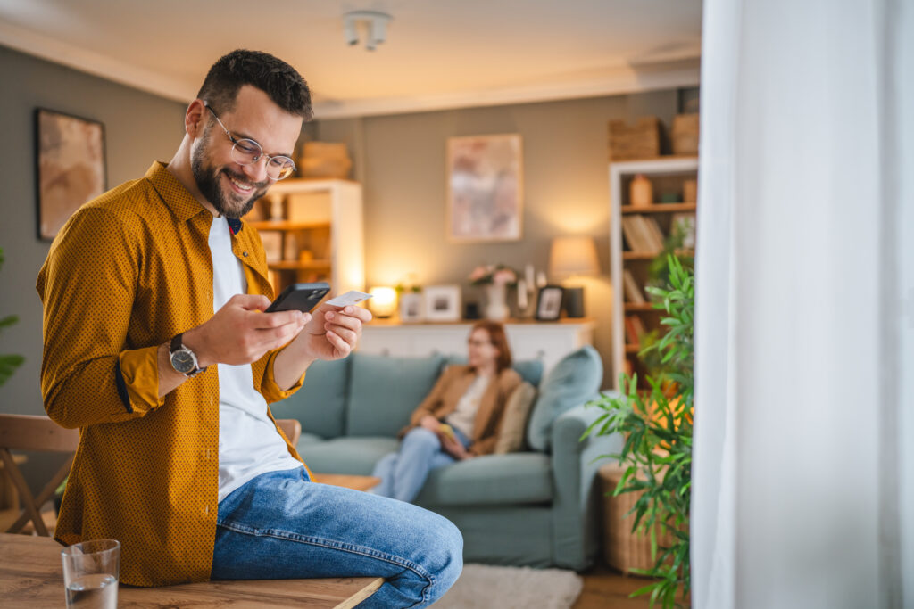A man checks his Belco Community Credit Union Premier Interest Checking Account balance from home using his mobile phone.