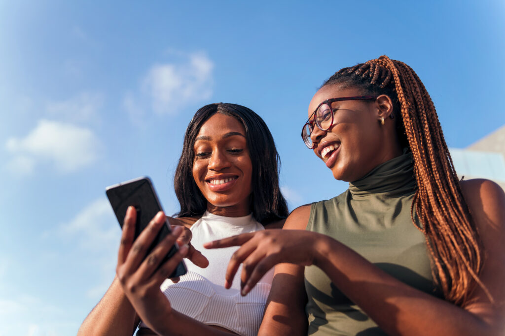 Two smiling women look at a smartphone screen