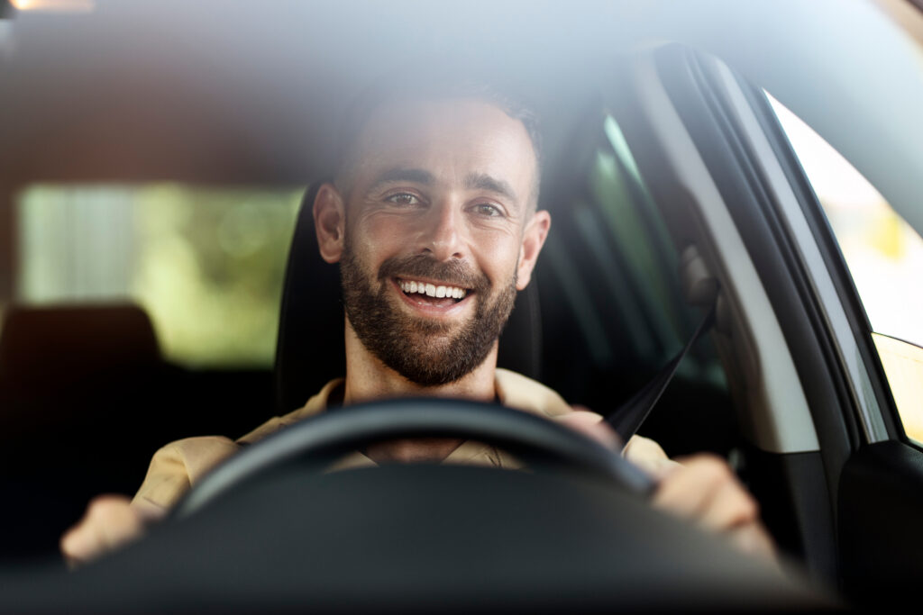A man smiling while driving a car.
