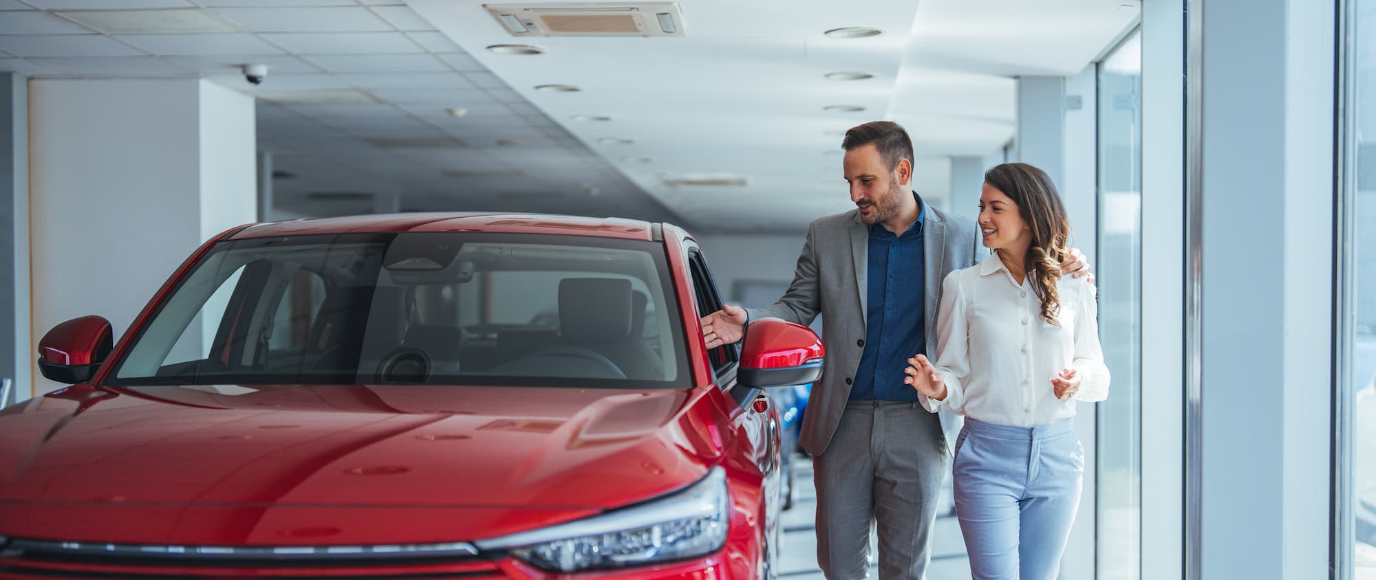 A couple checks out a used car at the dealership.